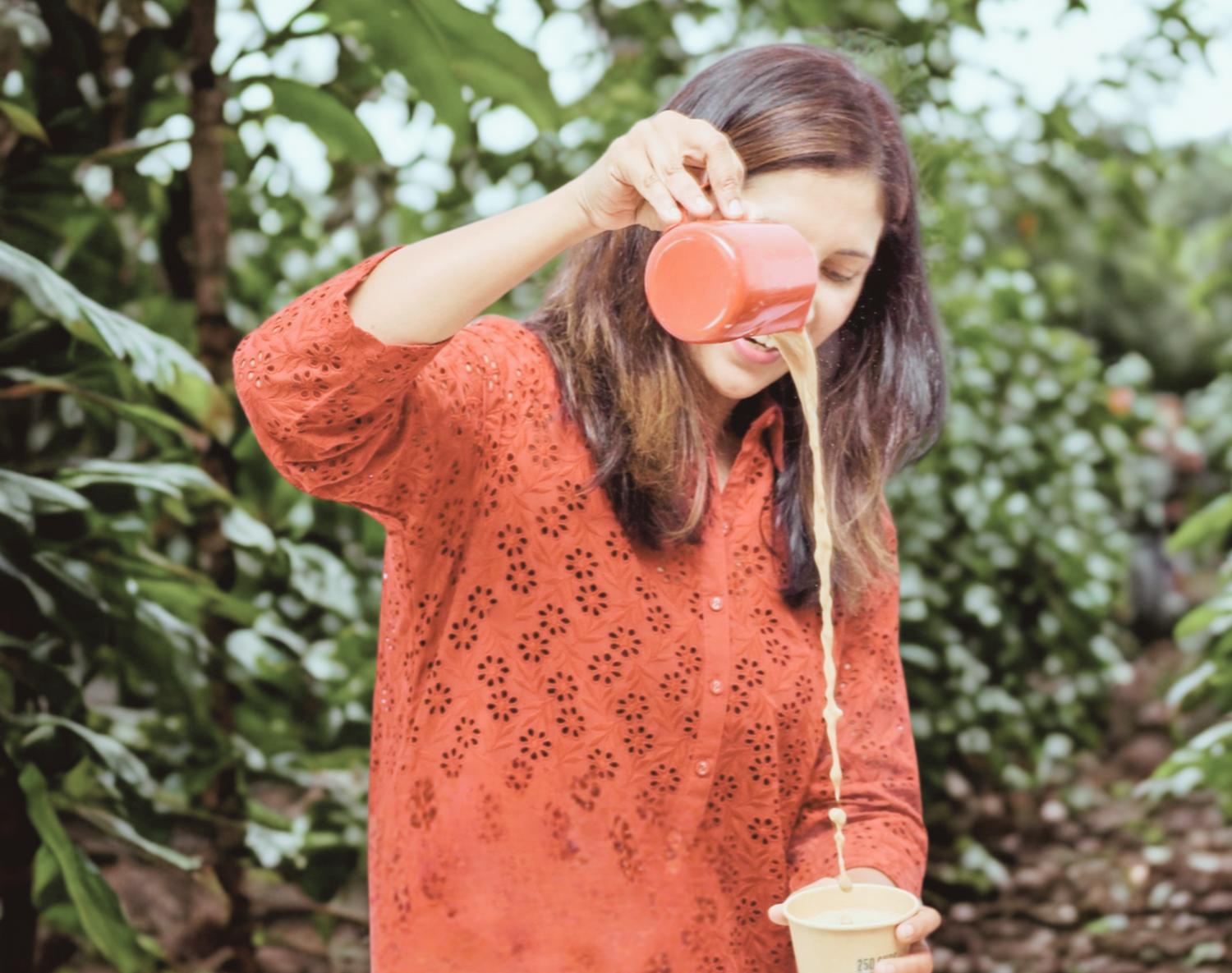 Woman in red shirt pouring filter coffee from a red container into a cup outdoors in Atlanta Georgia 